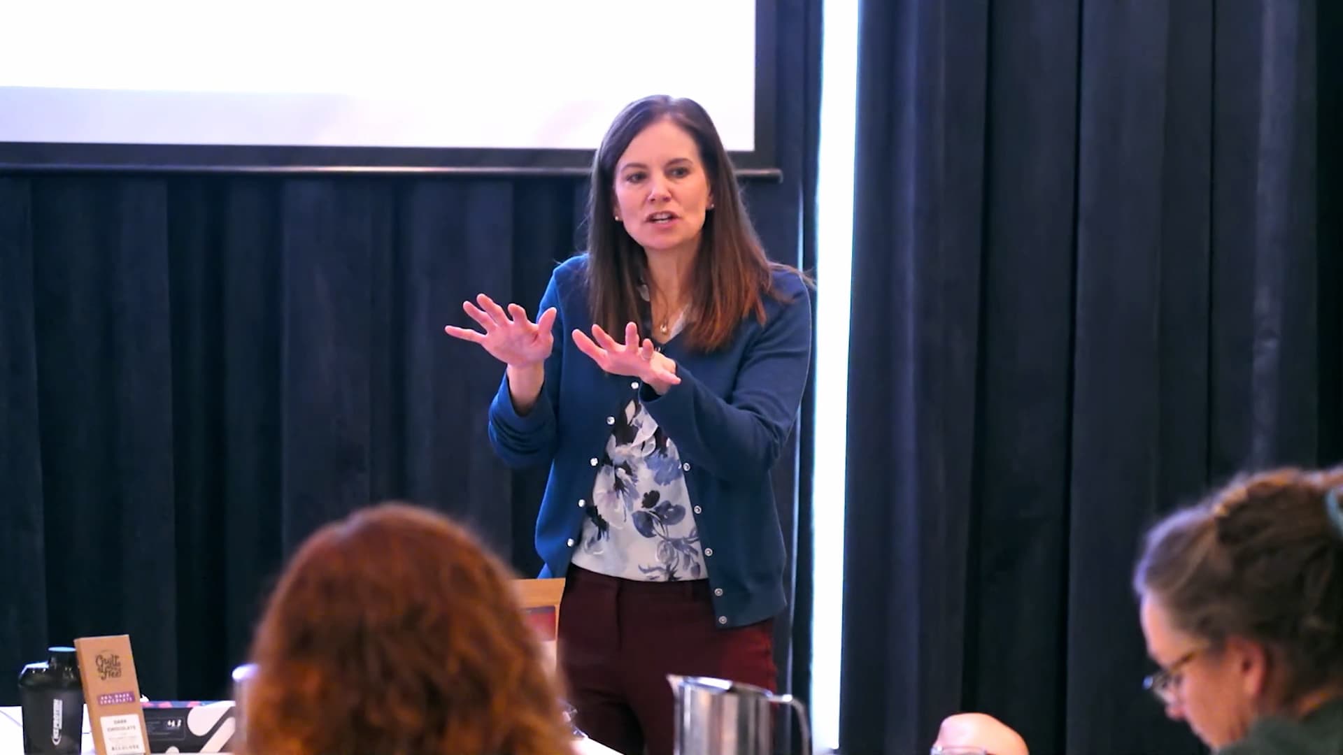 Dr Jonie Girouard presenting at a live workshop, hands gesturing to explain a concept